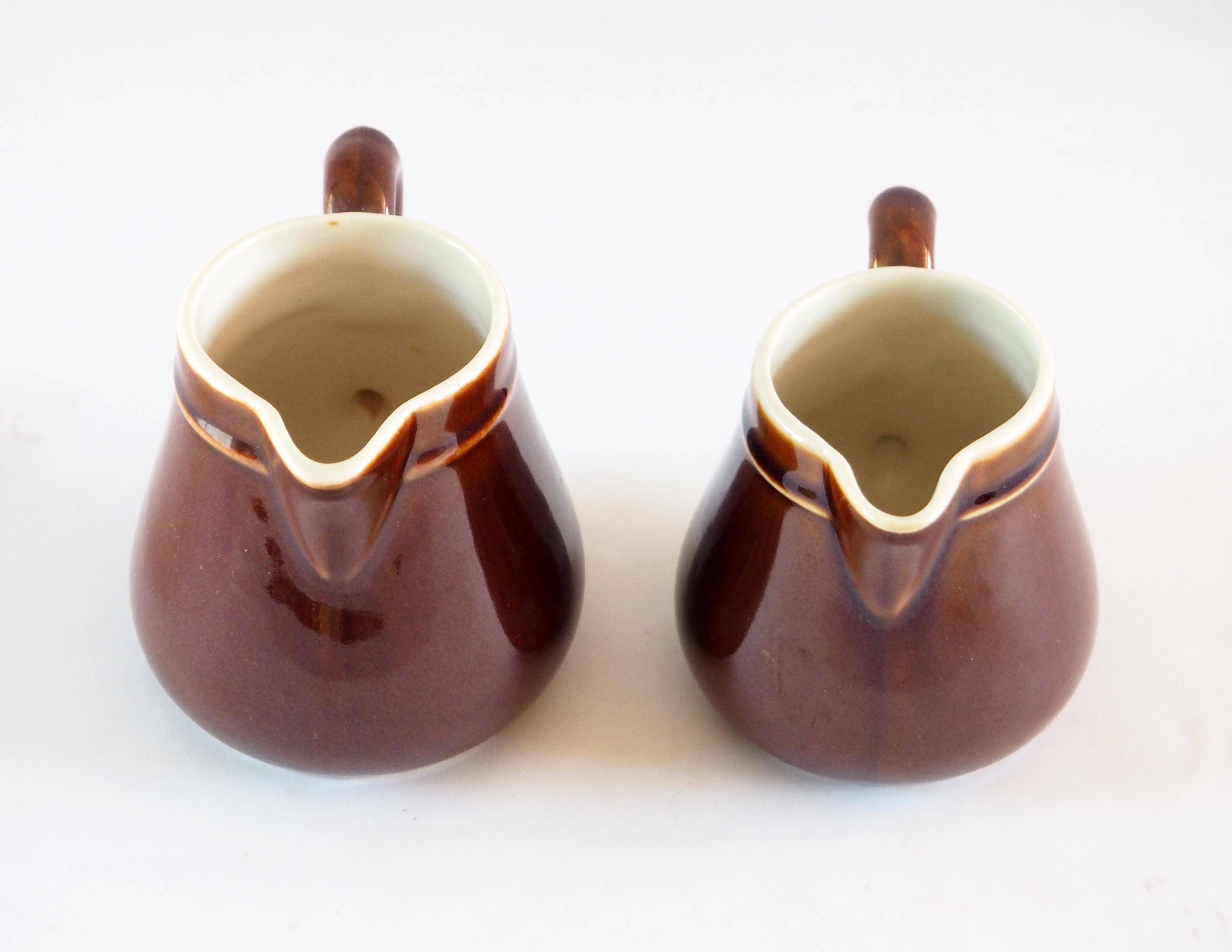 Duo of brown enamel pitchers