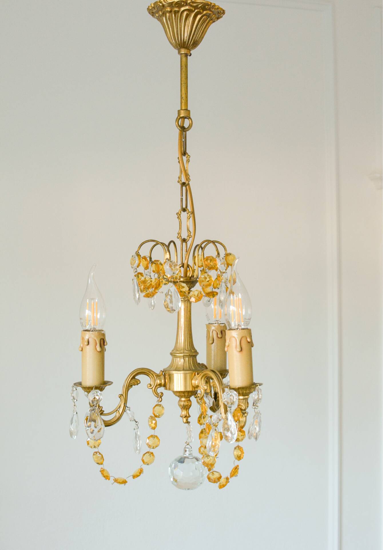 Small vintage brass chandelier with amber crystal pendants.