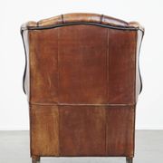 Cognac-colored sheep leather wingback chair finished with black piping
