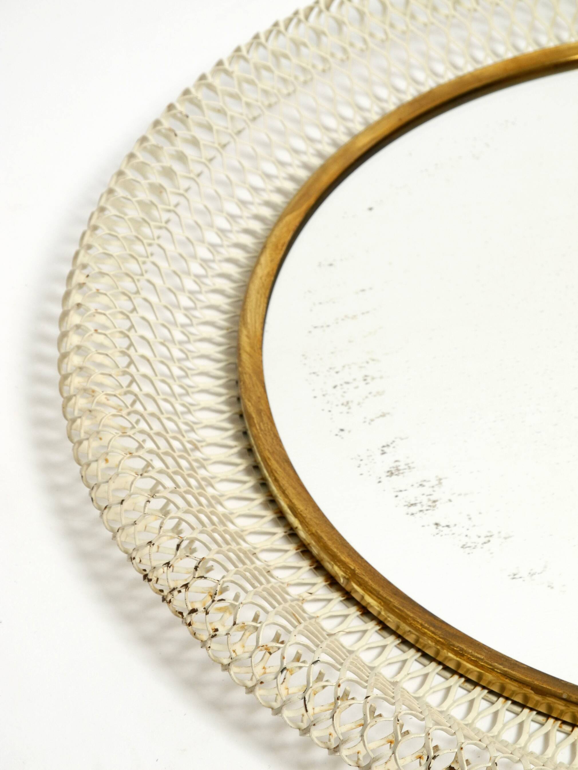 Mid Century Modern round wall mirror with a white expanded metal frame