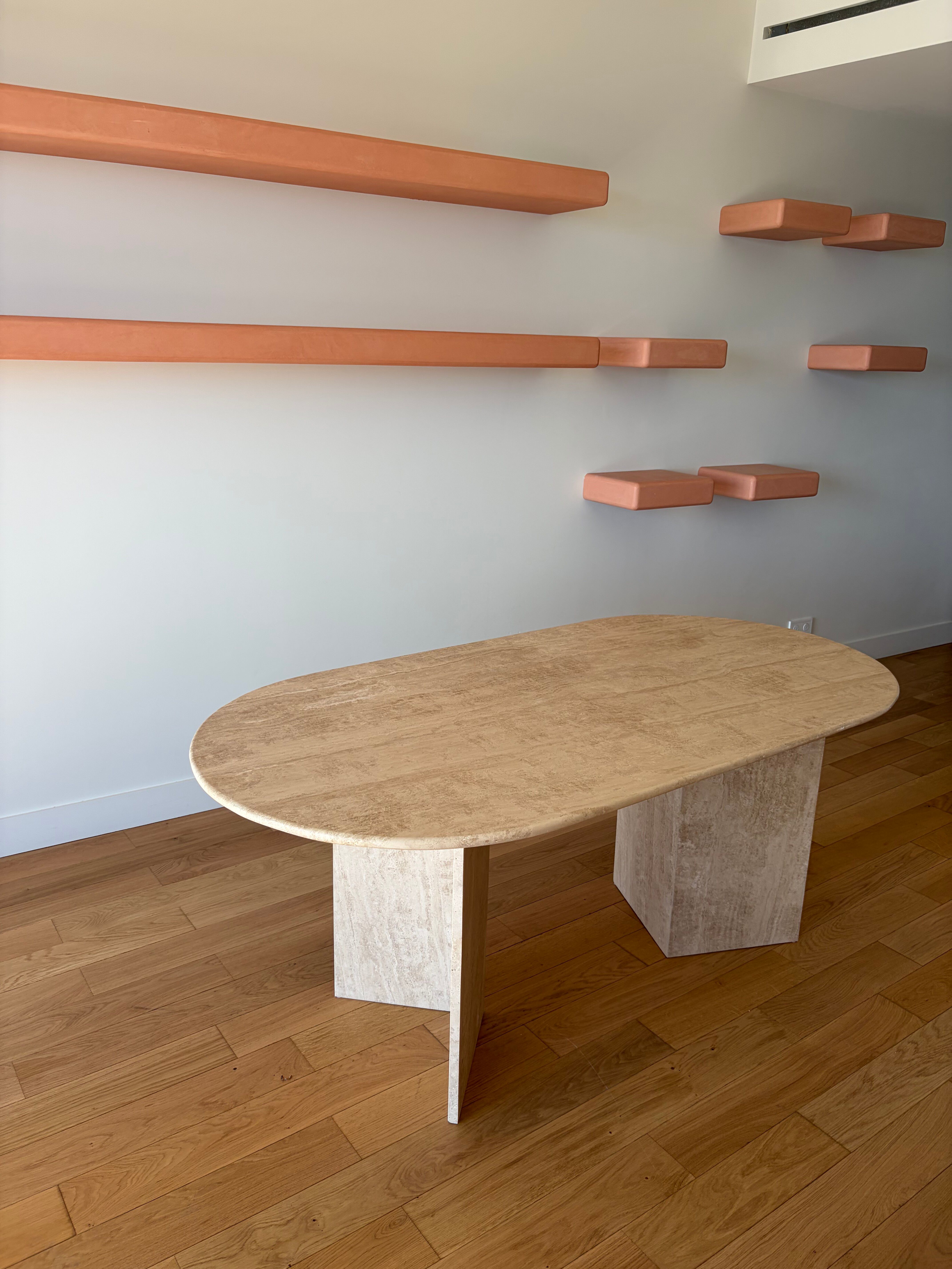 Oblong dining table in beige travertine.