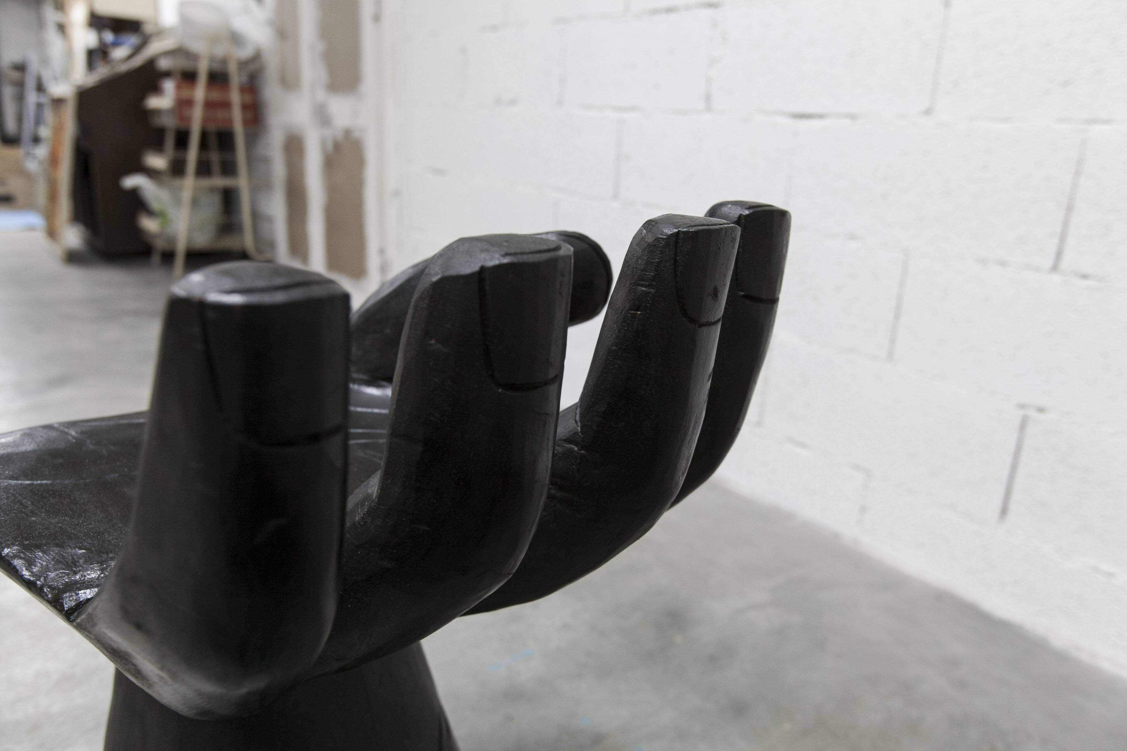 Black armchair chair in carved wood in the shape of a hand