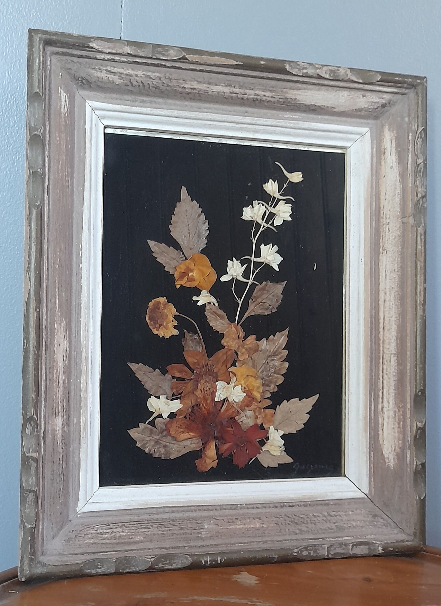 Wood frame dried flowers under glass, black background, vintage