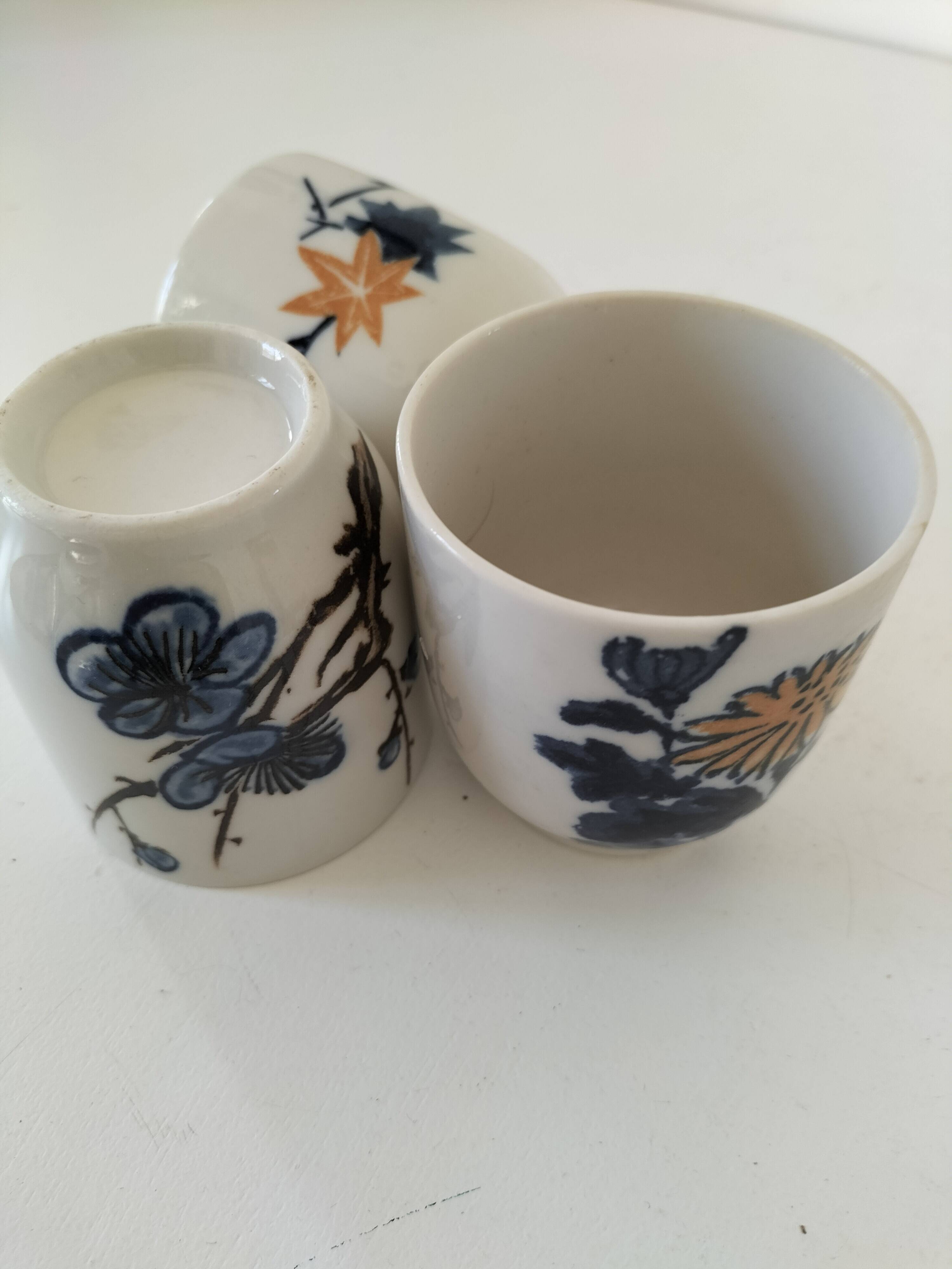 Set of three hand-painted porcelain cups with floral patterns.