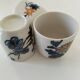 Set of three hand-painted porcelain cups with floral patterns.