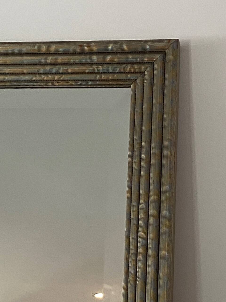 Textured embossed metal wall mirror with bevelled mirror.