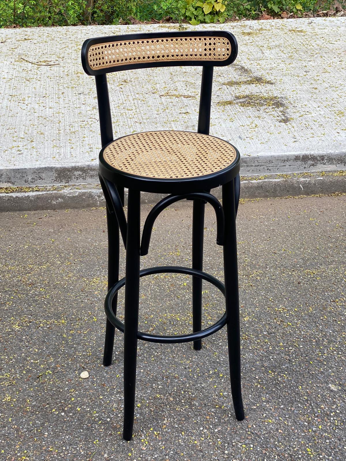 High bistro bar stool in curved black wood with a cane backrest.