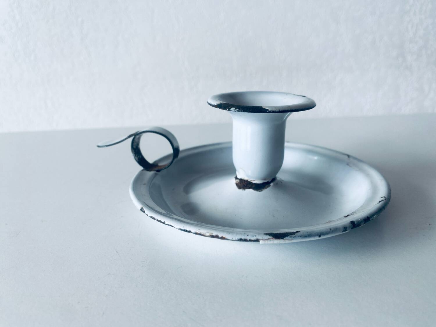 Old candle holder in white enameled metal