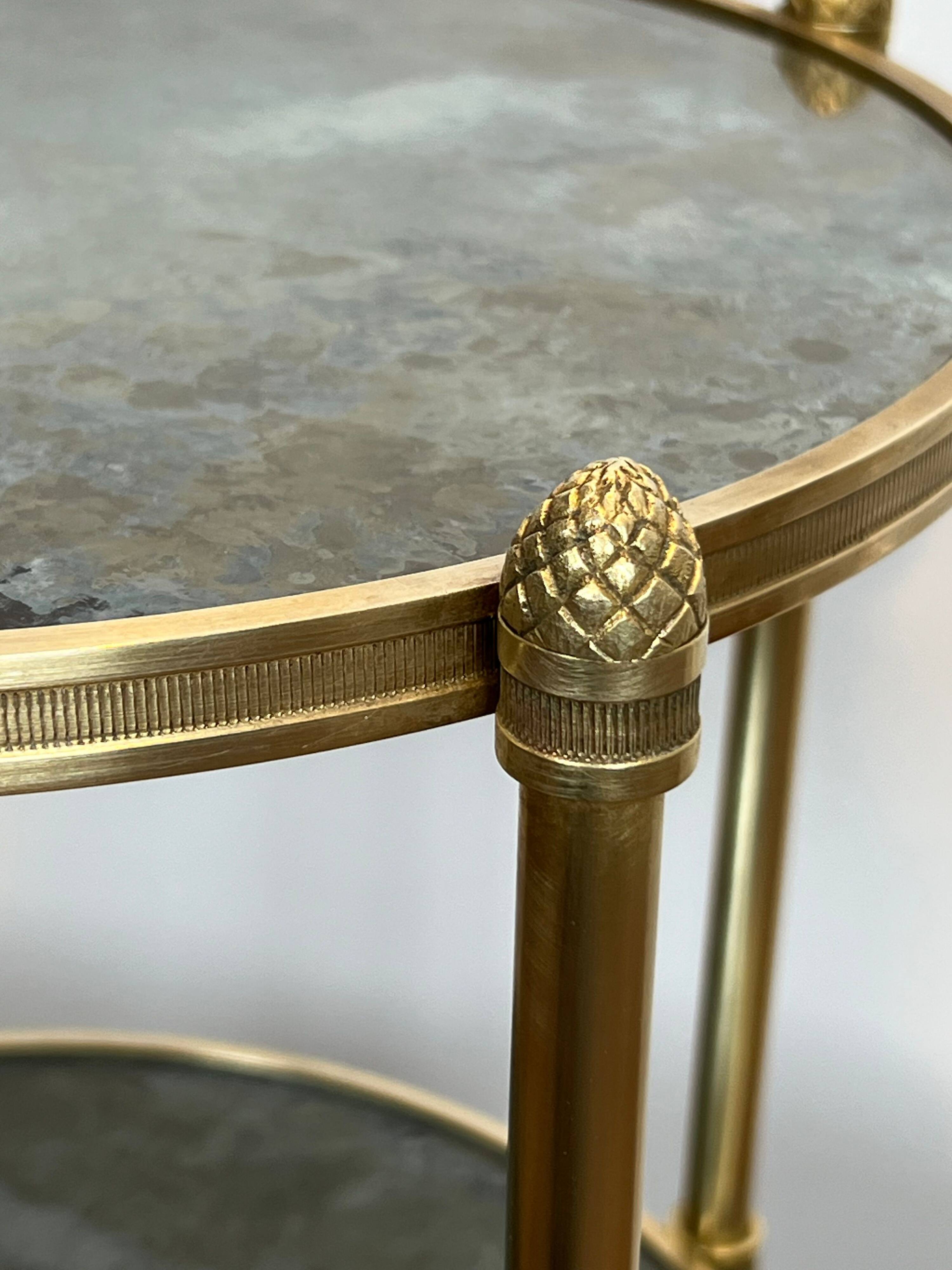 Round bronze side table with triple shelves of églomisé mirrors from Maison Baguès