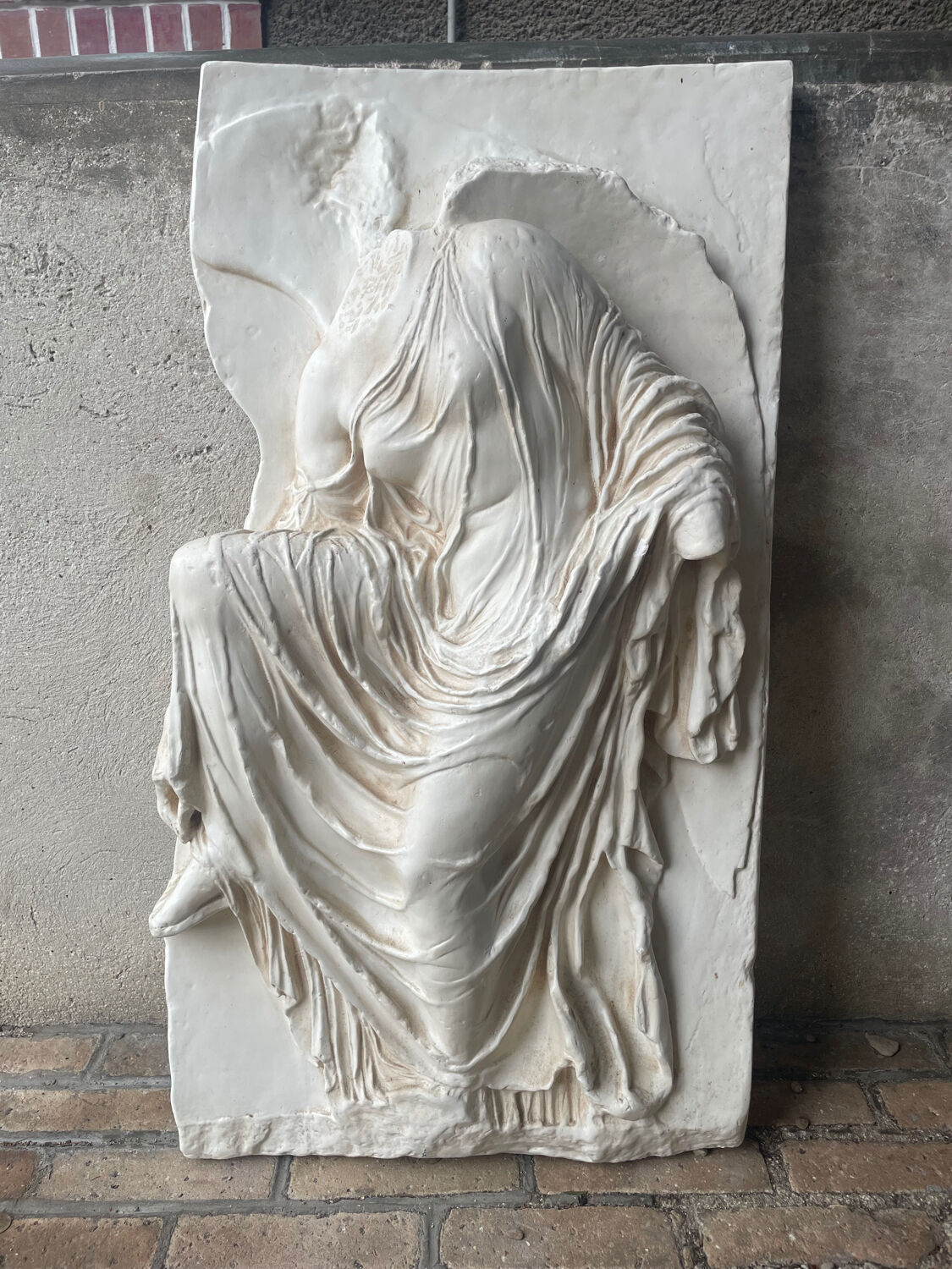 Ancient plaster bas-relief of Nike fastening her sandal.