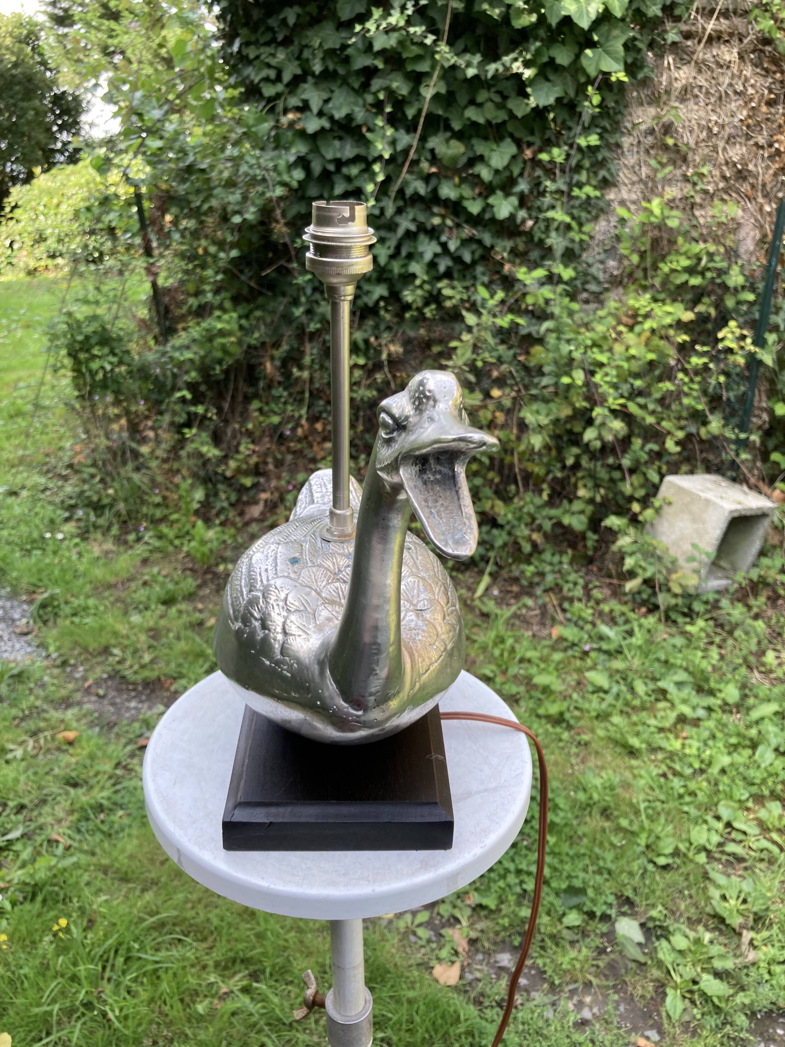Old vintage lamp representing a duck in silver metal with wooden base