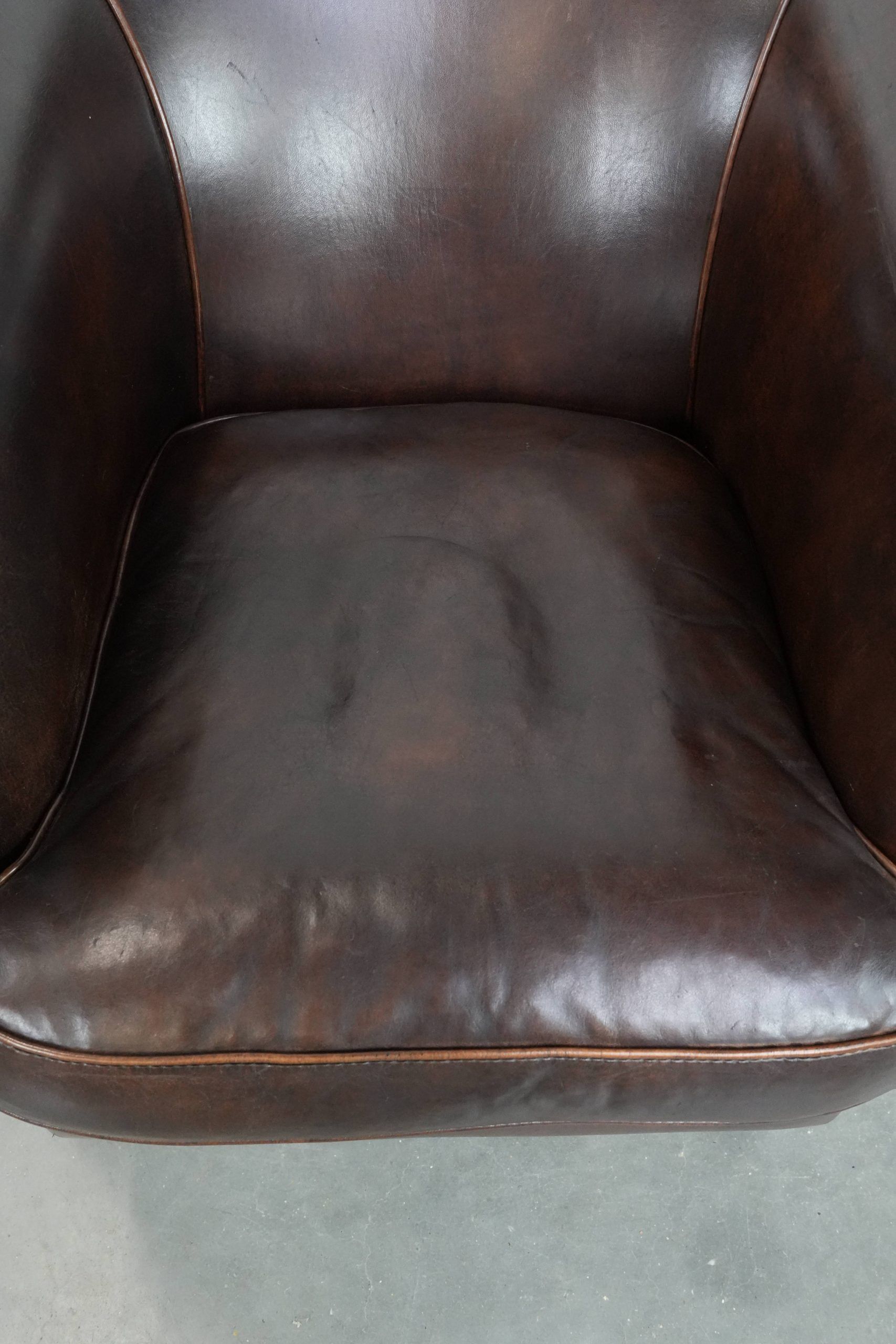 Dark brown vintage club armchair in English style made of sheepskin leather
