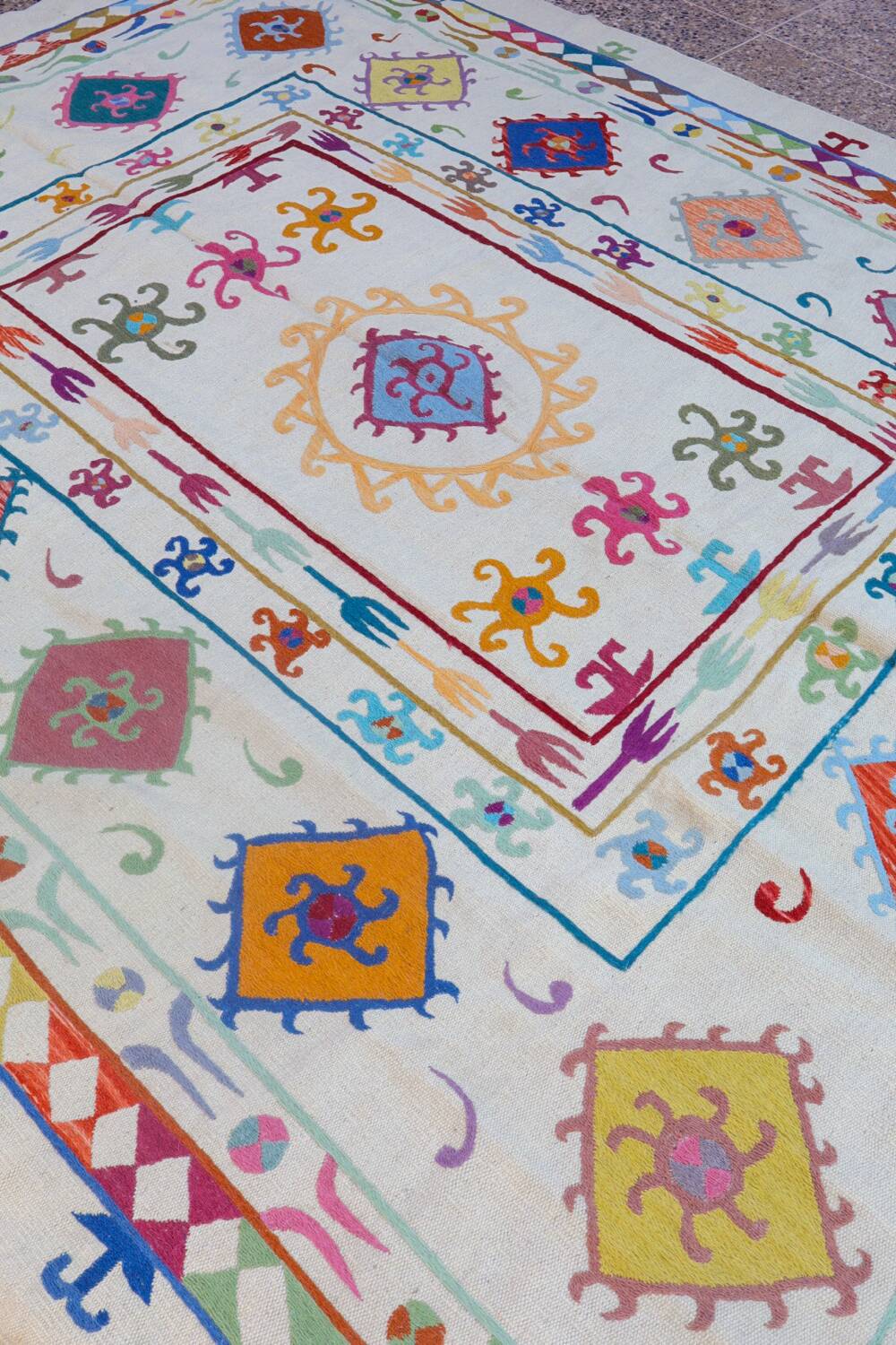 White suzani kilim rug with multi-colored embroidered patterns