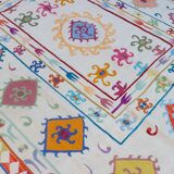 White suzani kilim rug with multi-colored embroidered patterns