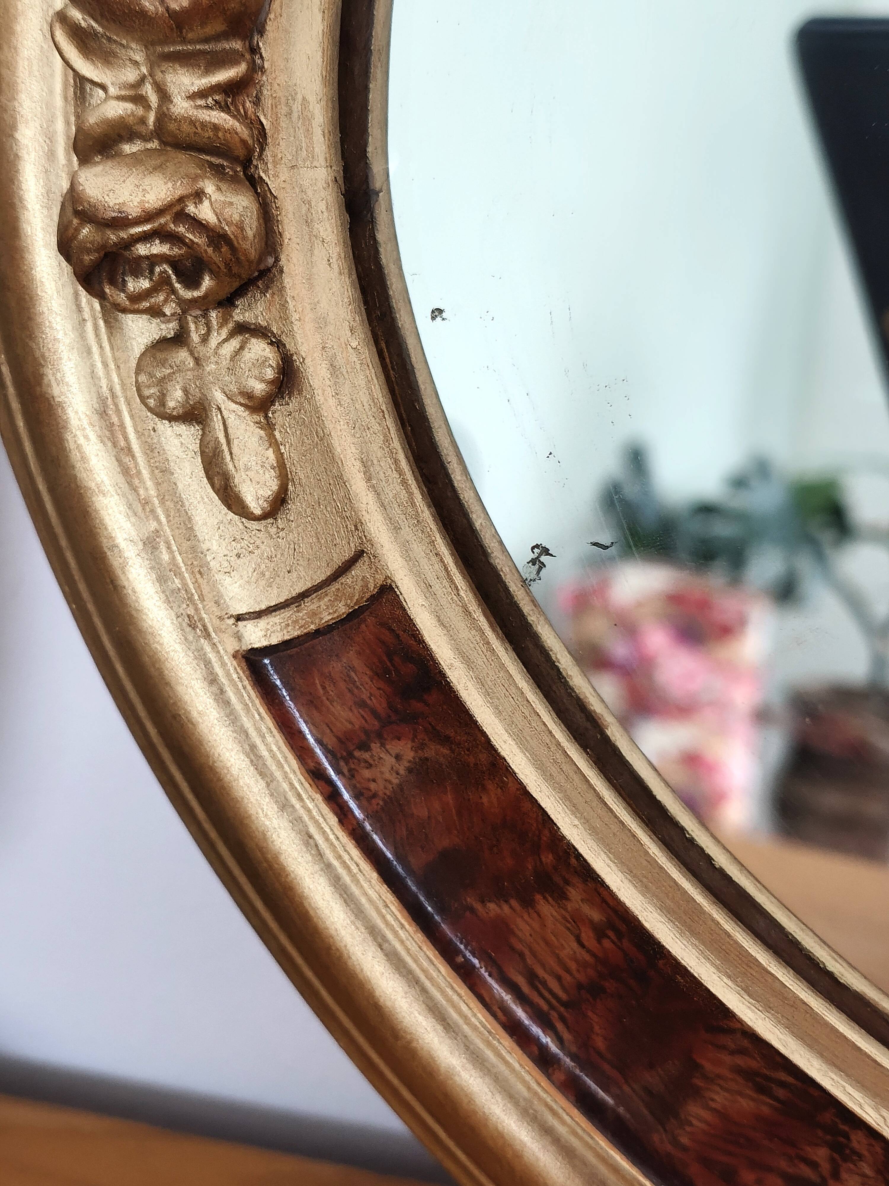 Antique medallion mirror with a gilded and relief-carved frame.