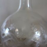Antique glass carafe with a round belly and floral neck.