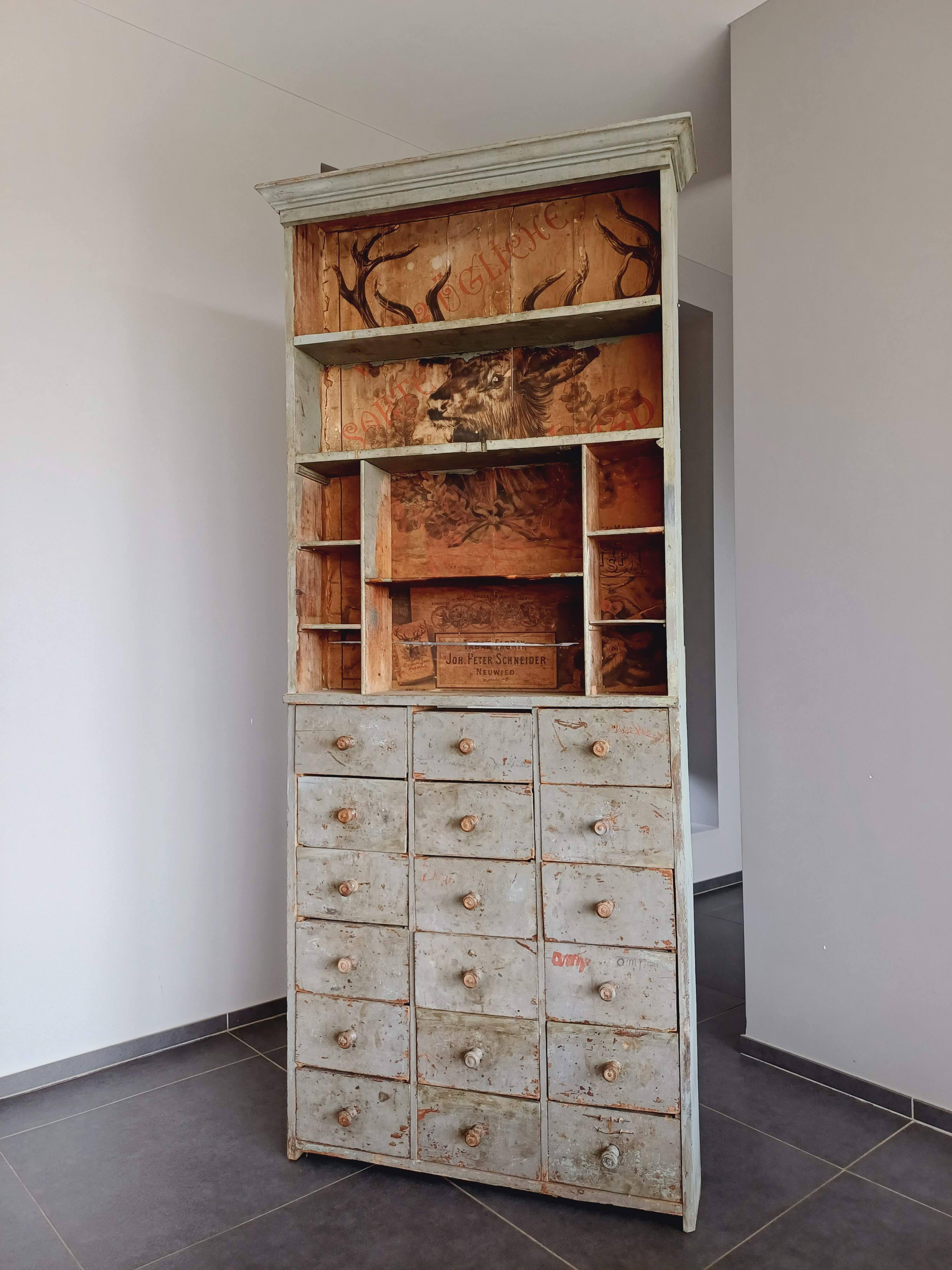 Craft cabinet with drawers with a very old tobacco advertisement in the background