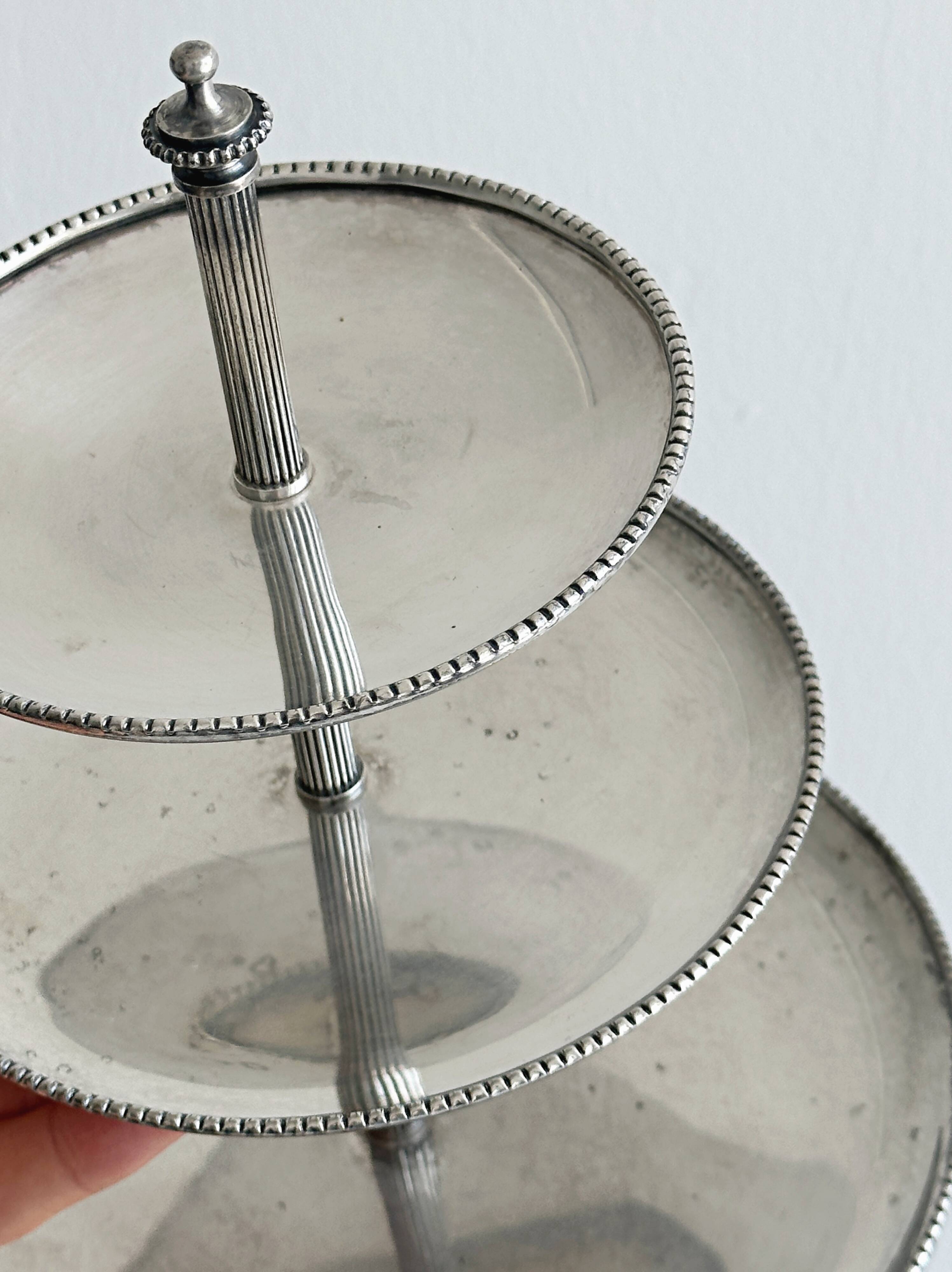 Vintage three-tiered serving stand in patinated silver metal.