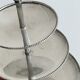 Vintage three-tiered serving stand in patinated silver metal.