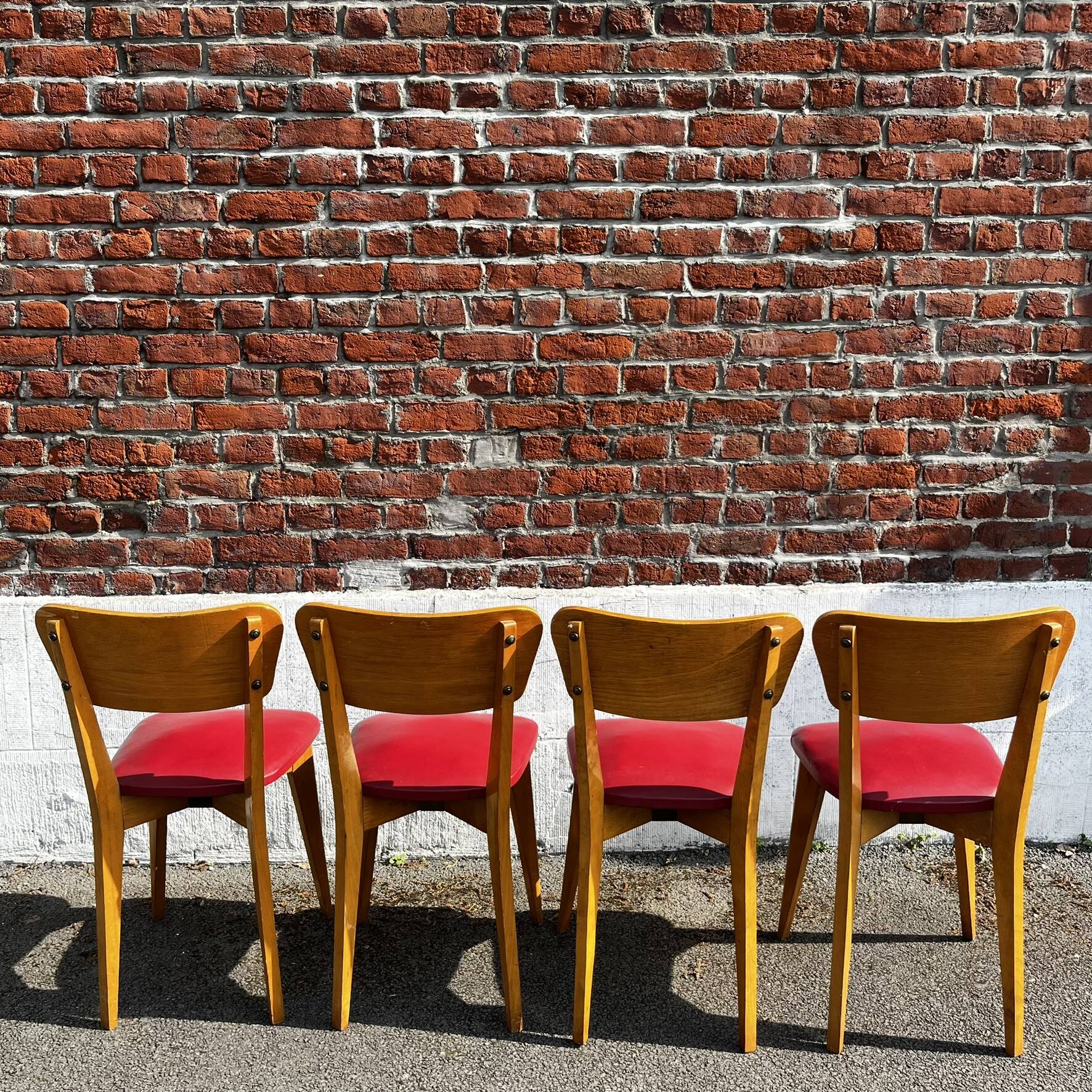 Set of 4 vintage bistro chairs in wood and red faux leather, with splayed legs.