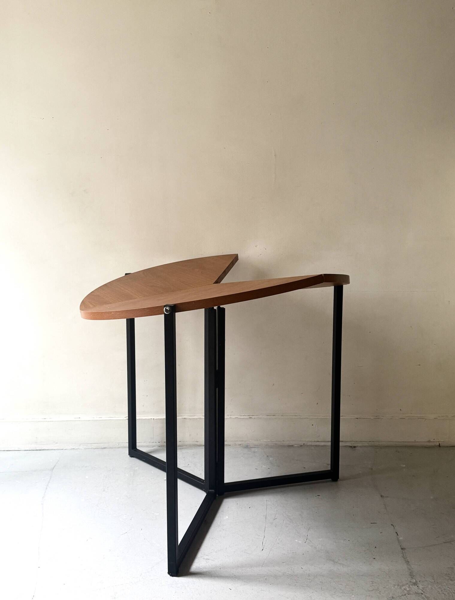 Modernist round folding dining table in wood and metal.