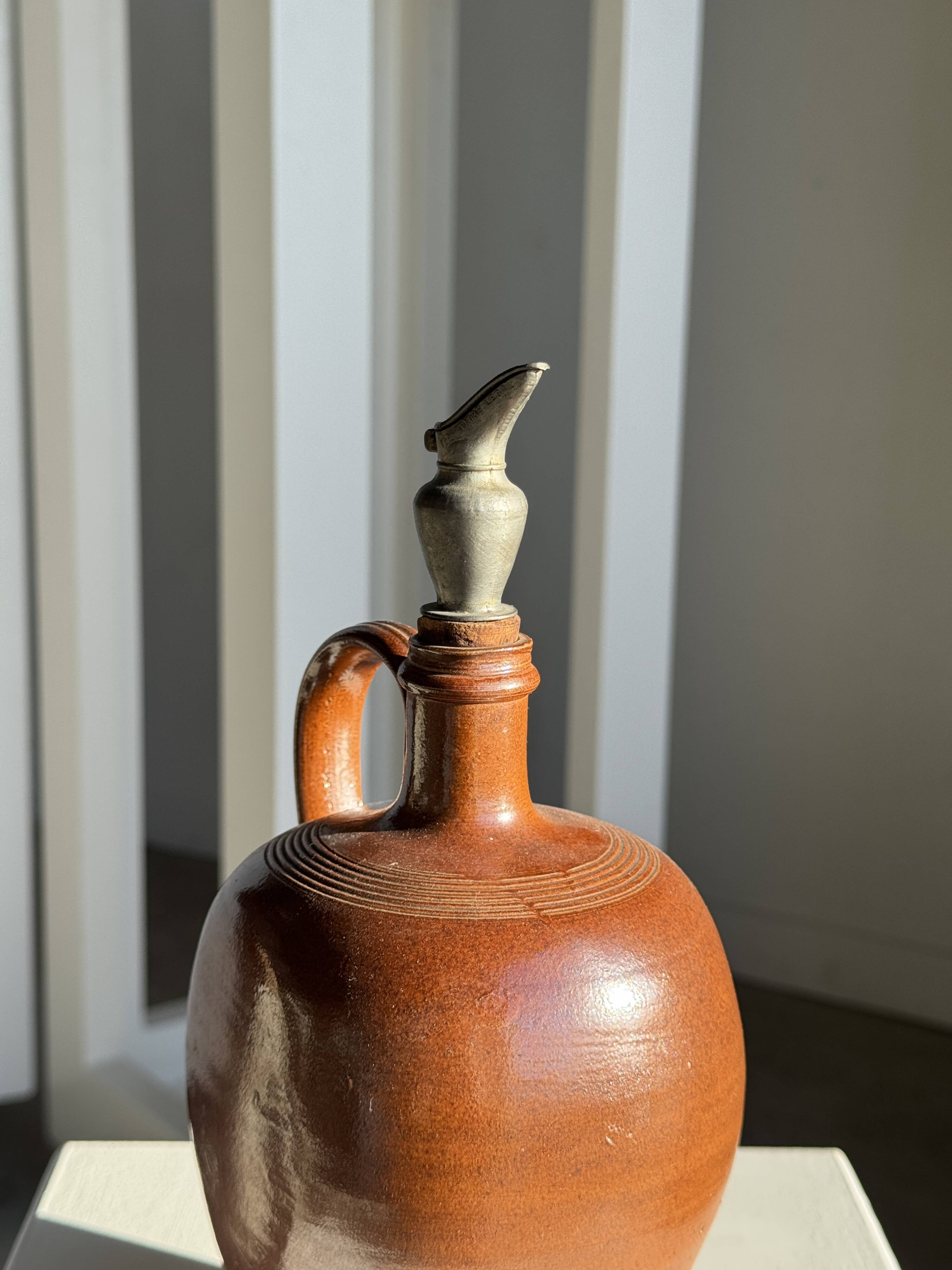 Ancient stoneware jug with a pewter spout.