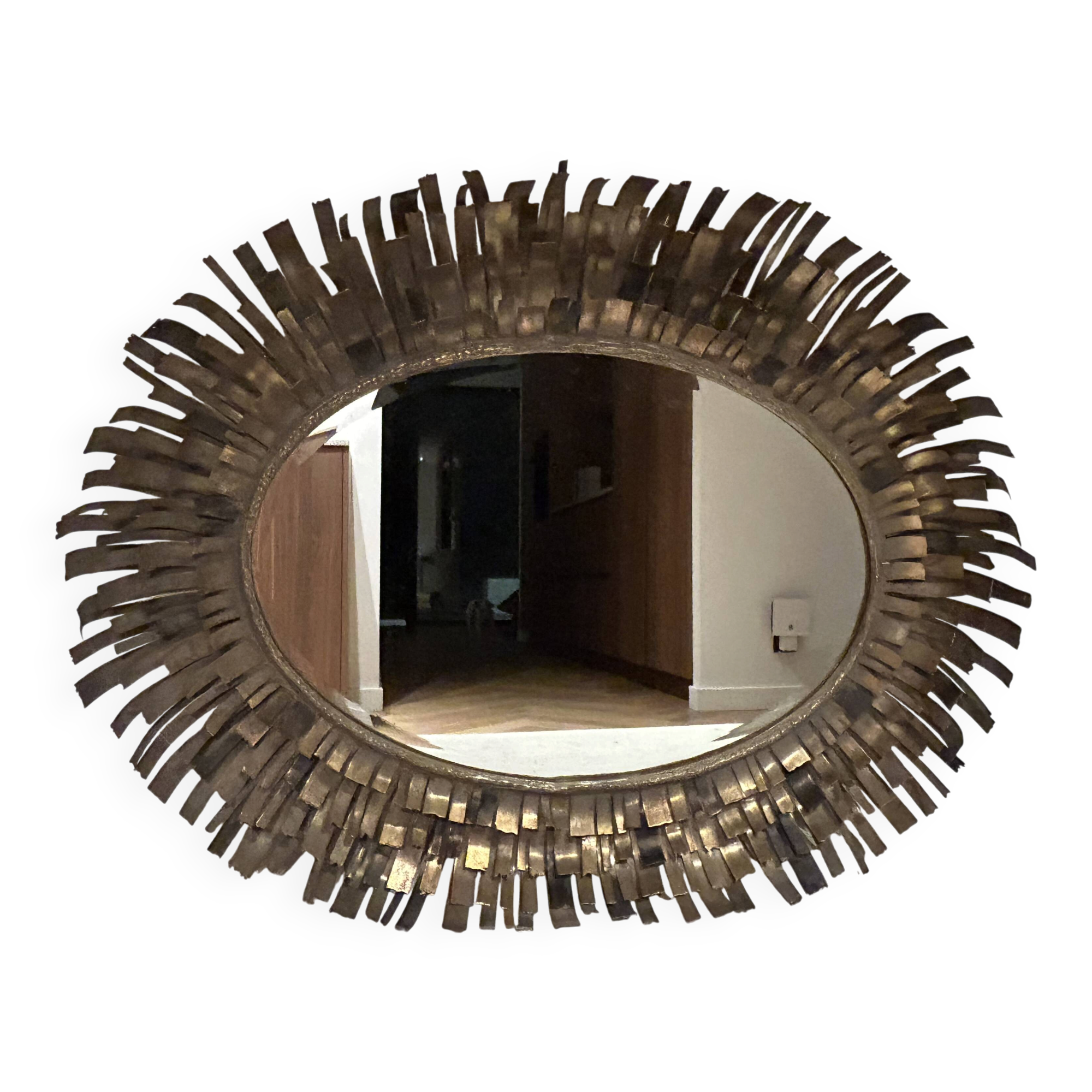 Large oval sun mirror in patinated gold metal.