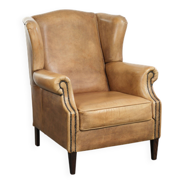 Fauteuil à oreilles en cuir de vache confortable avec un look anglais intemporel.