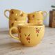 Large vintage ceramic mug in yellow with hand-painted flowers.