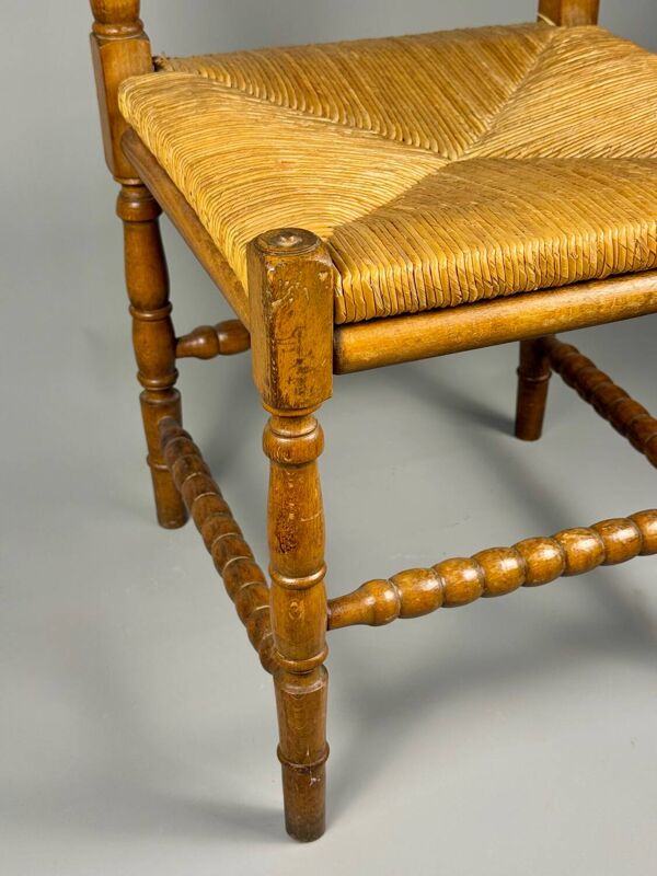 Chaise d'angle vintage en bois avec assise en paille tissée.