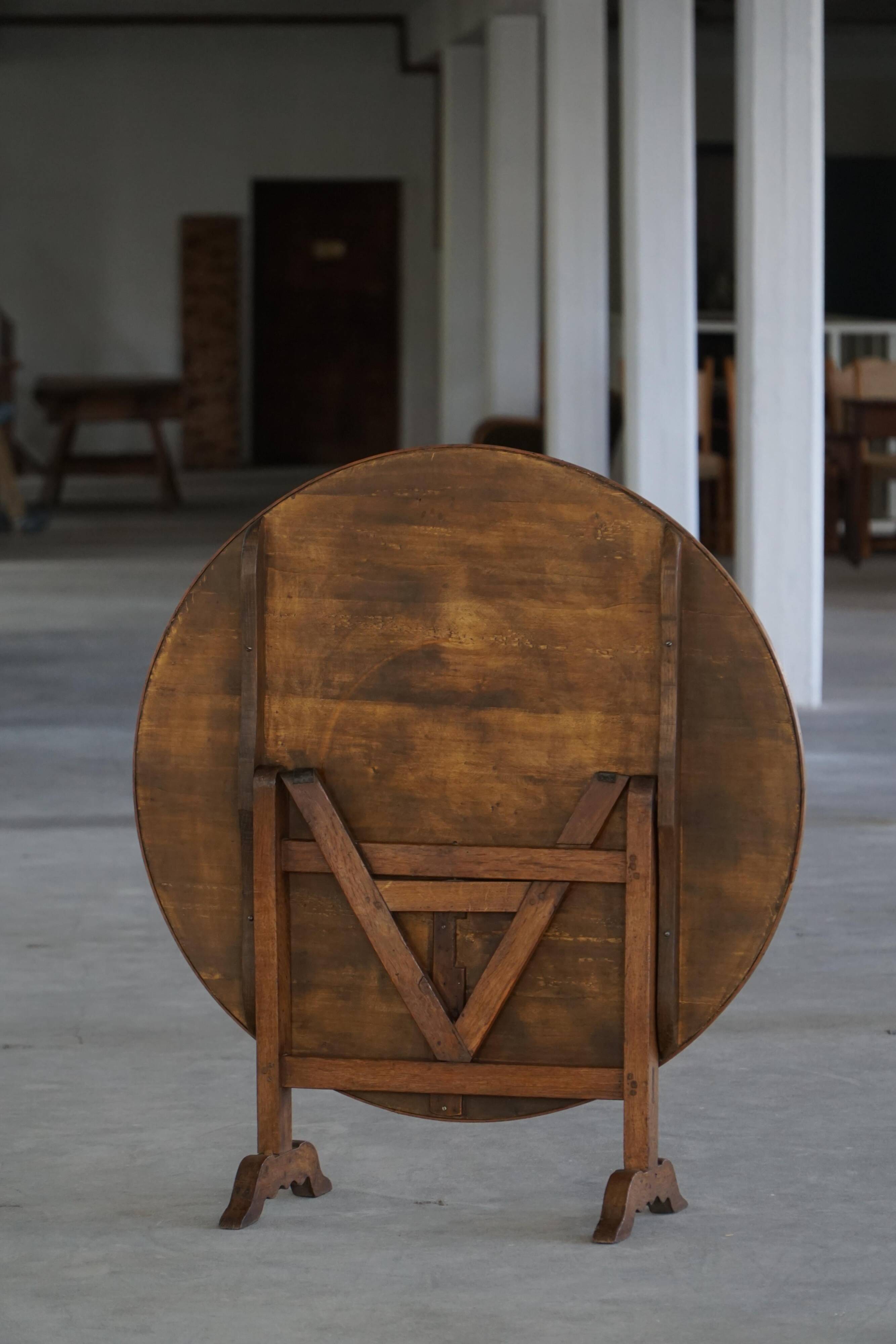 19th-century French round wine table with an adjustable top and floral textile surface.