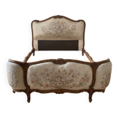 Double bed in Louis XVI style made of wood and floral fabric.