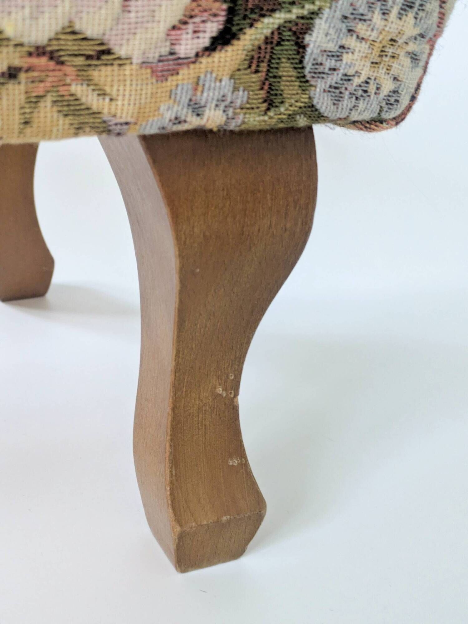 Large vintage upholstered footstool with curved legs.