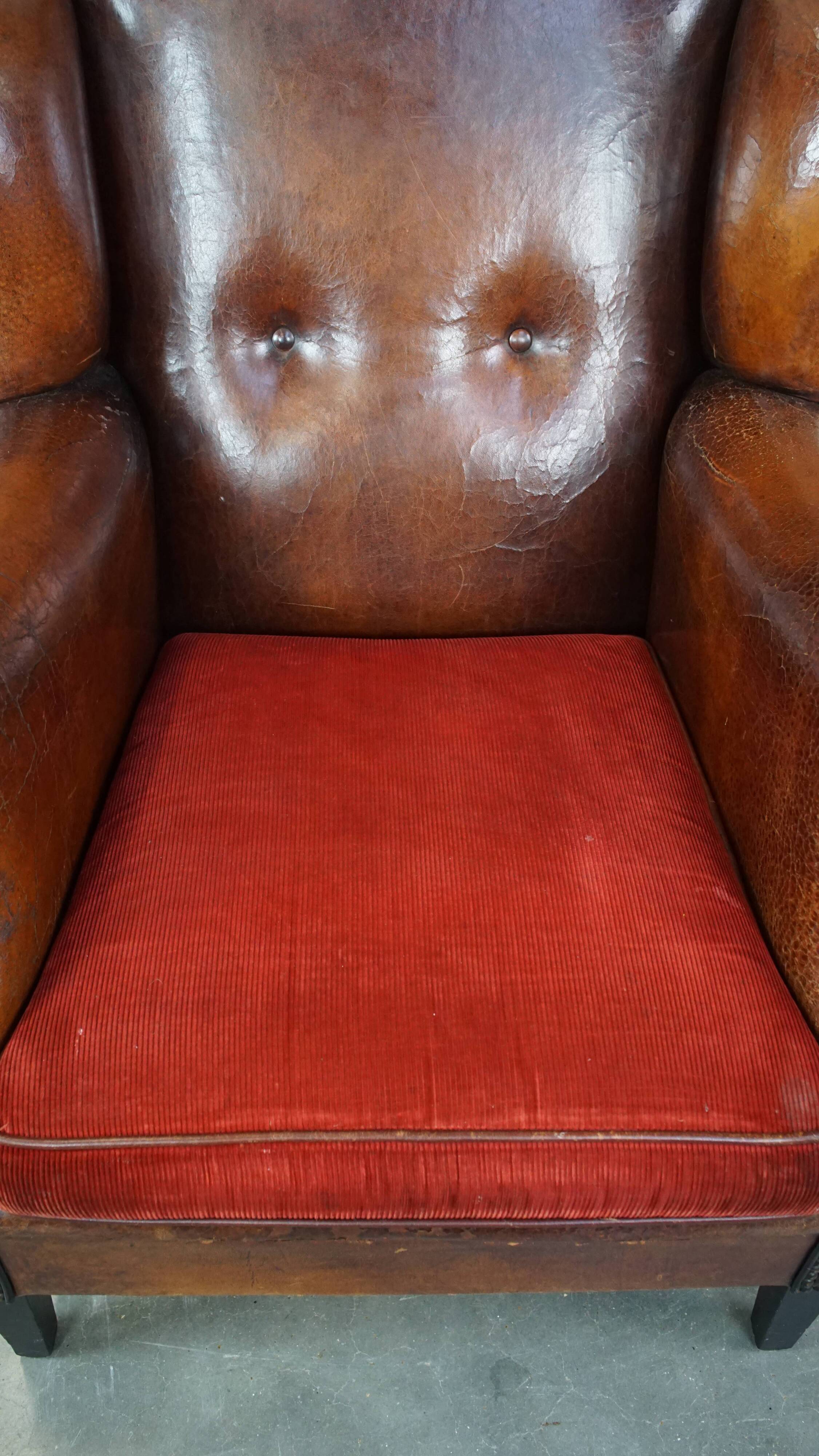 Sheepskin leather wingback chair with a red corduroy seat cushion