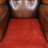 Sheepskin leather wingback chair with a red corduroy seat cushion