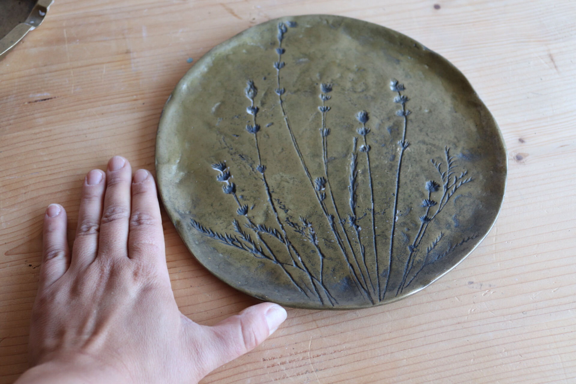 Decorative wall plaque in brass with a floral design.