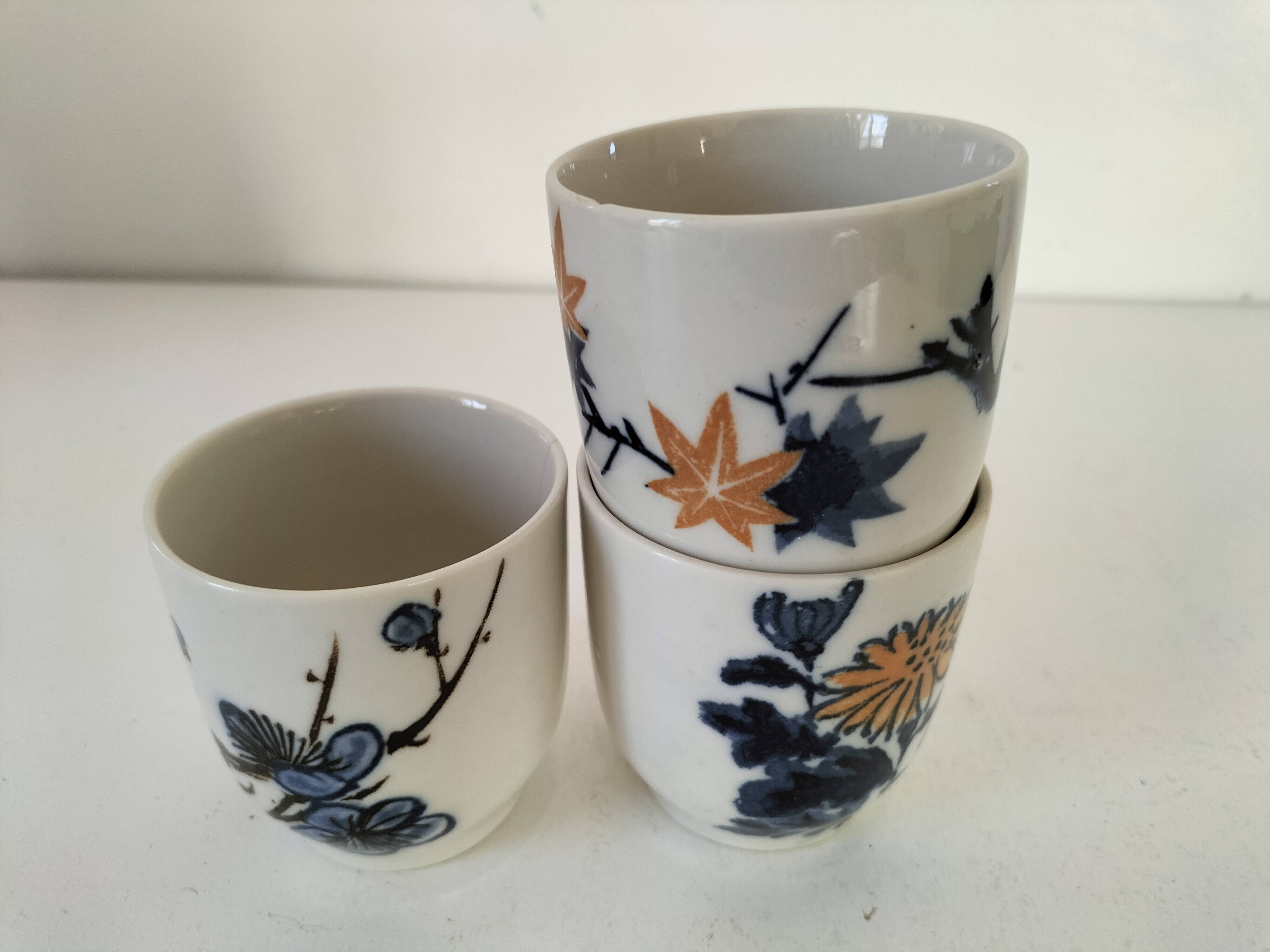 Set of three hand-painted porcelain cups with floral patterns.