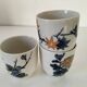 Set of three hand-painted porcelain cups with floral patterns.