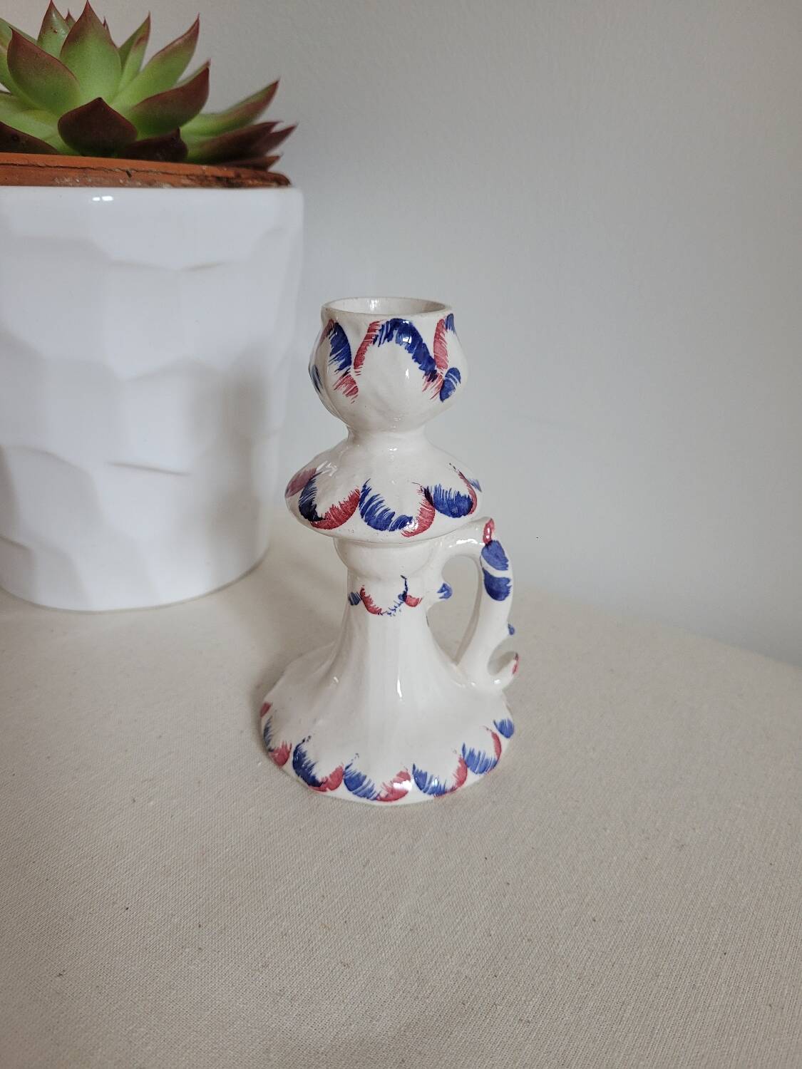 Ceramic candlestick with red and blue decoration.