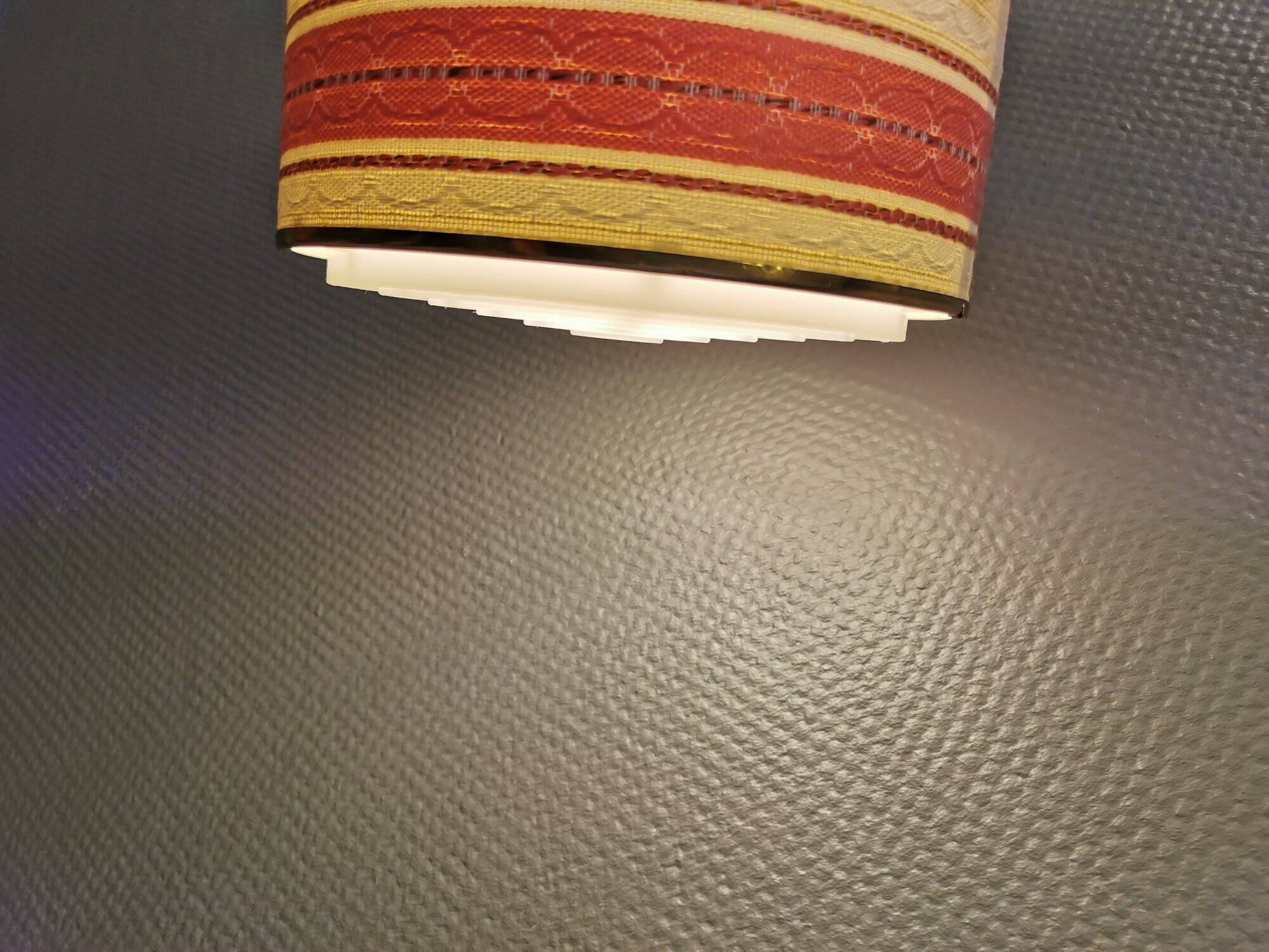 Hanging lamp with brass-coloured details, made of fabric with intact plastic bottom grille.