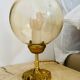 2 bedside lamps with round amber glass globes and gold metal.
