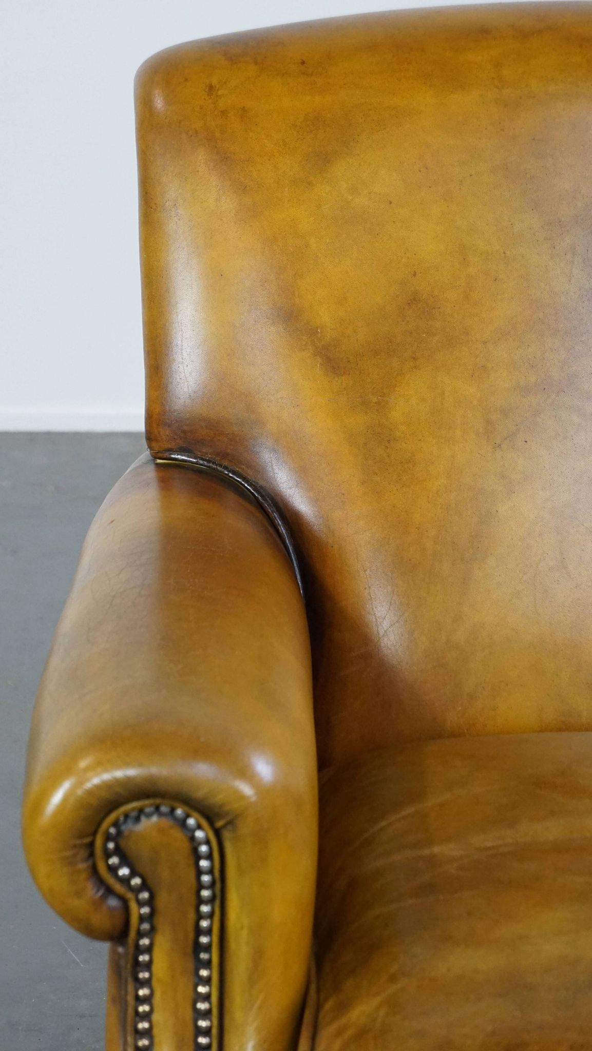 Comfortable large yellow English-style leather armchair with a fine finish and decorative nails