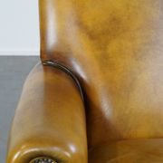 Comfortable large yellow English-style leather armchair with a fine finish and decorative nails