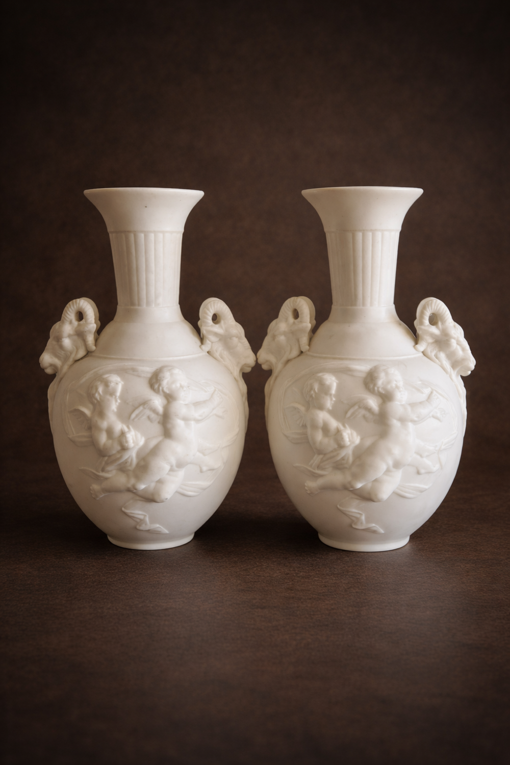 Paire de vases en biscuit decor putti et tête de bélier