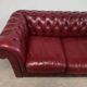 Red two-seater chesterfield sofa