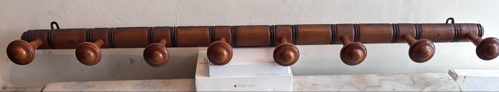 Wall-mounted coat rack with 8 turned wooden hooks in faux bamboo style.