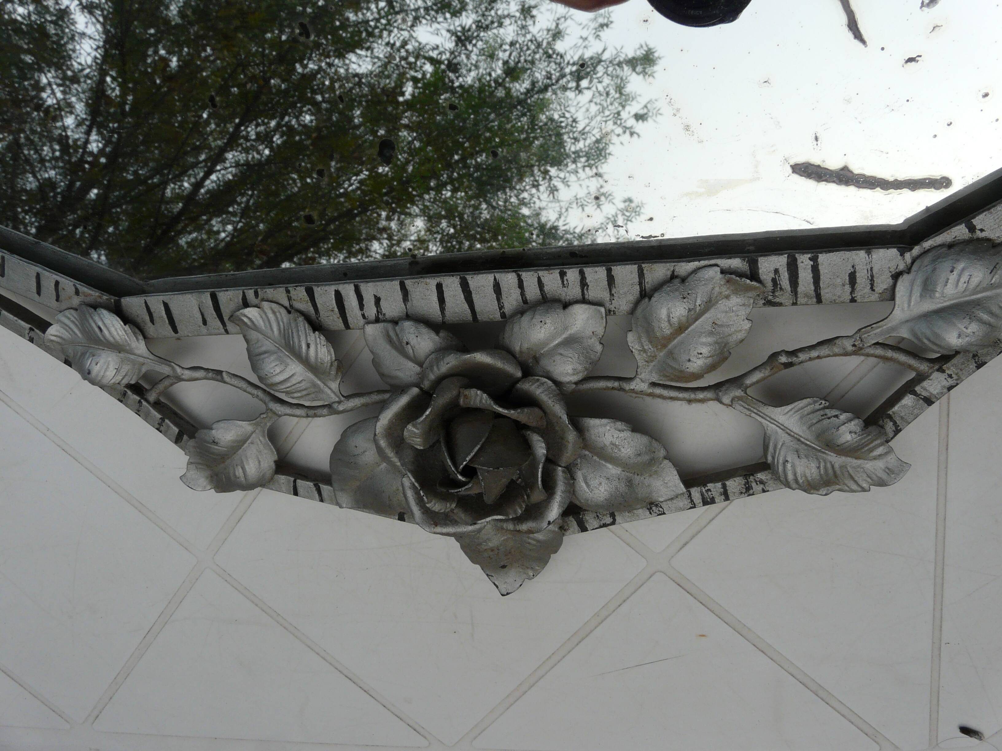 Beveled mirror with art-deco wrought iron frame and floral decor with hanging chain