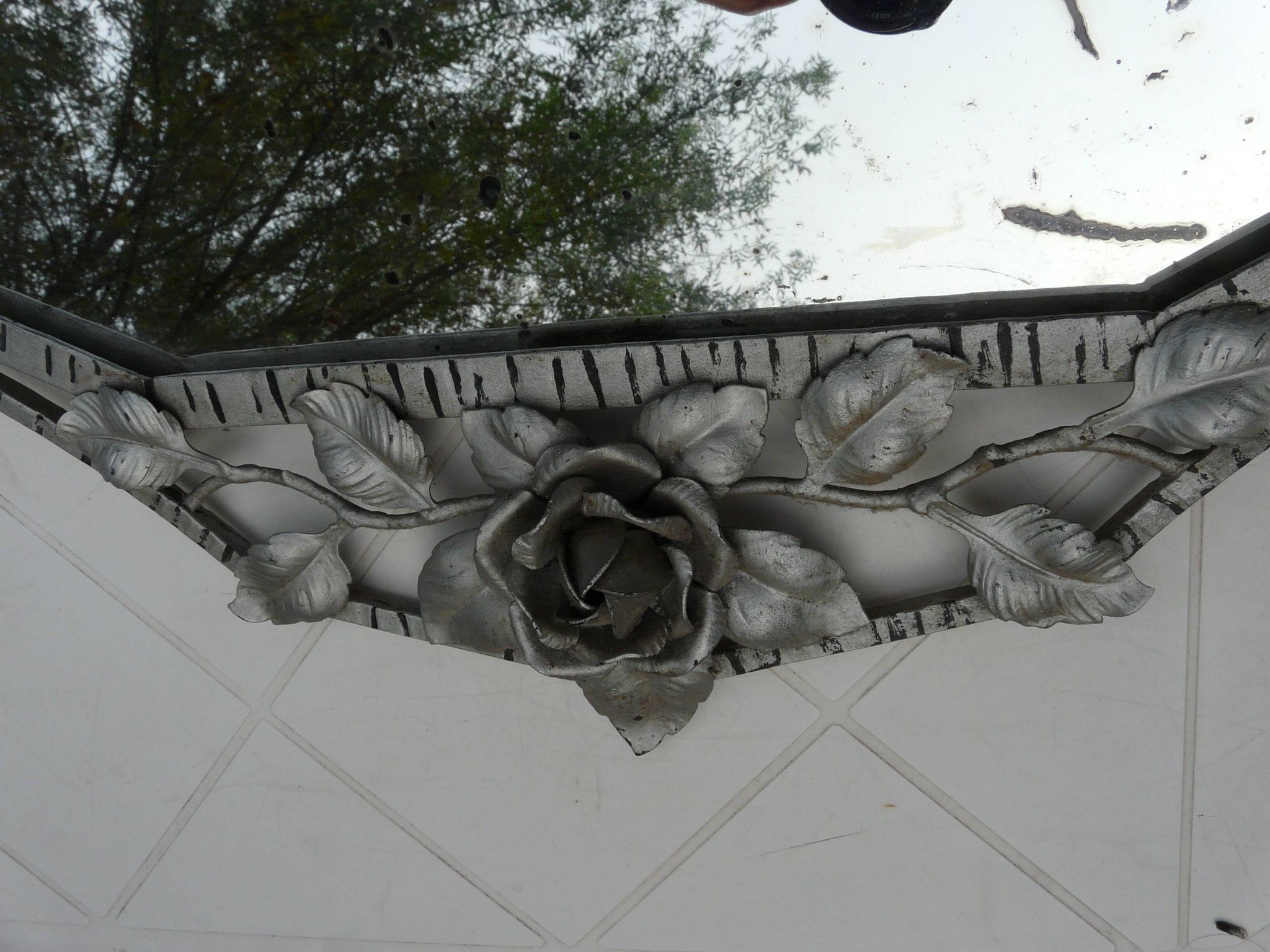 Beveled mirror with art-deco wrought iron frame and floral decor with hanging chain