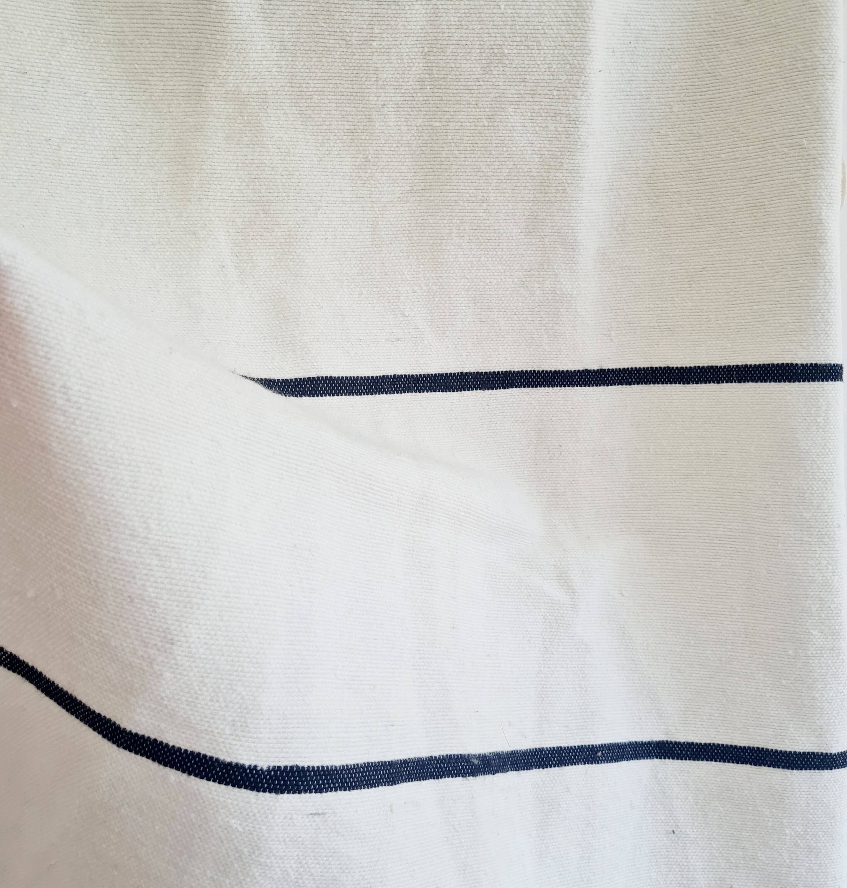 Handwoven throw with black stripes and pom-poms