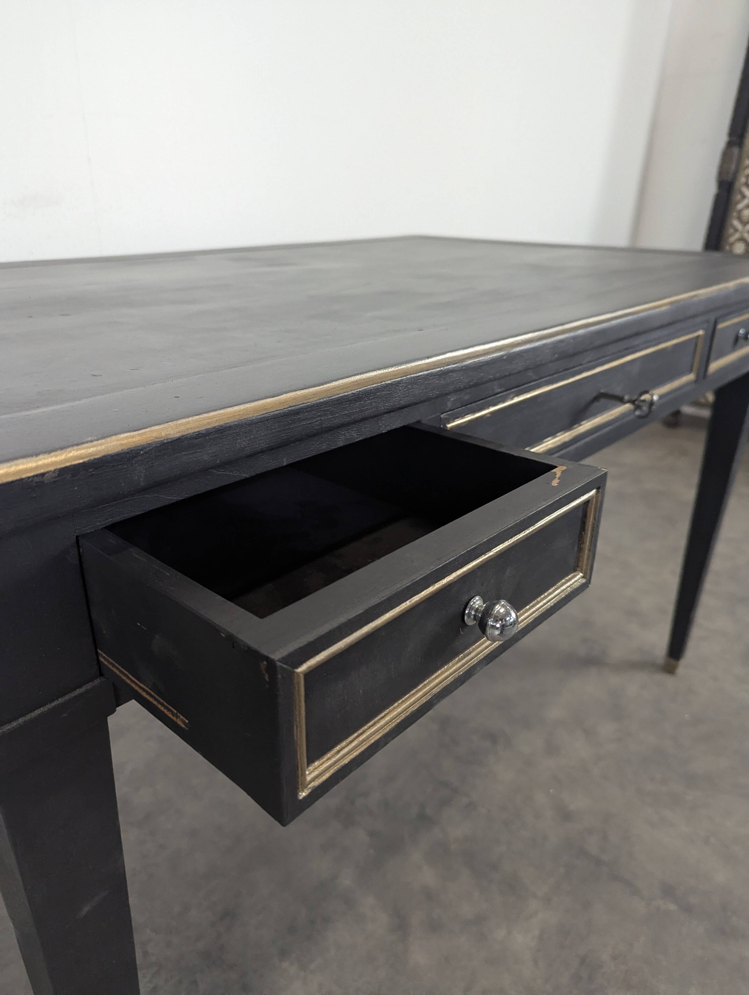 Large flat desk in Louis XVI style, black lacquered with gold highlights.